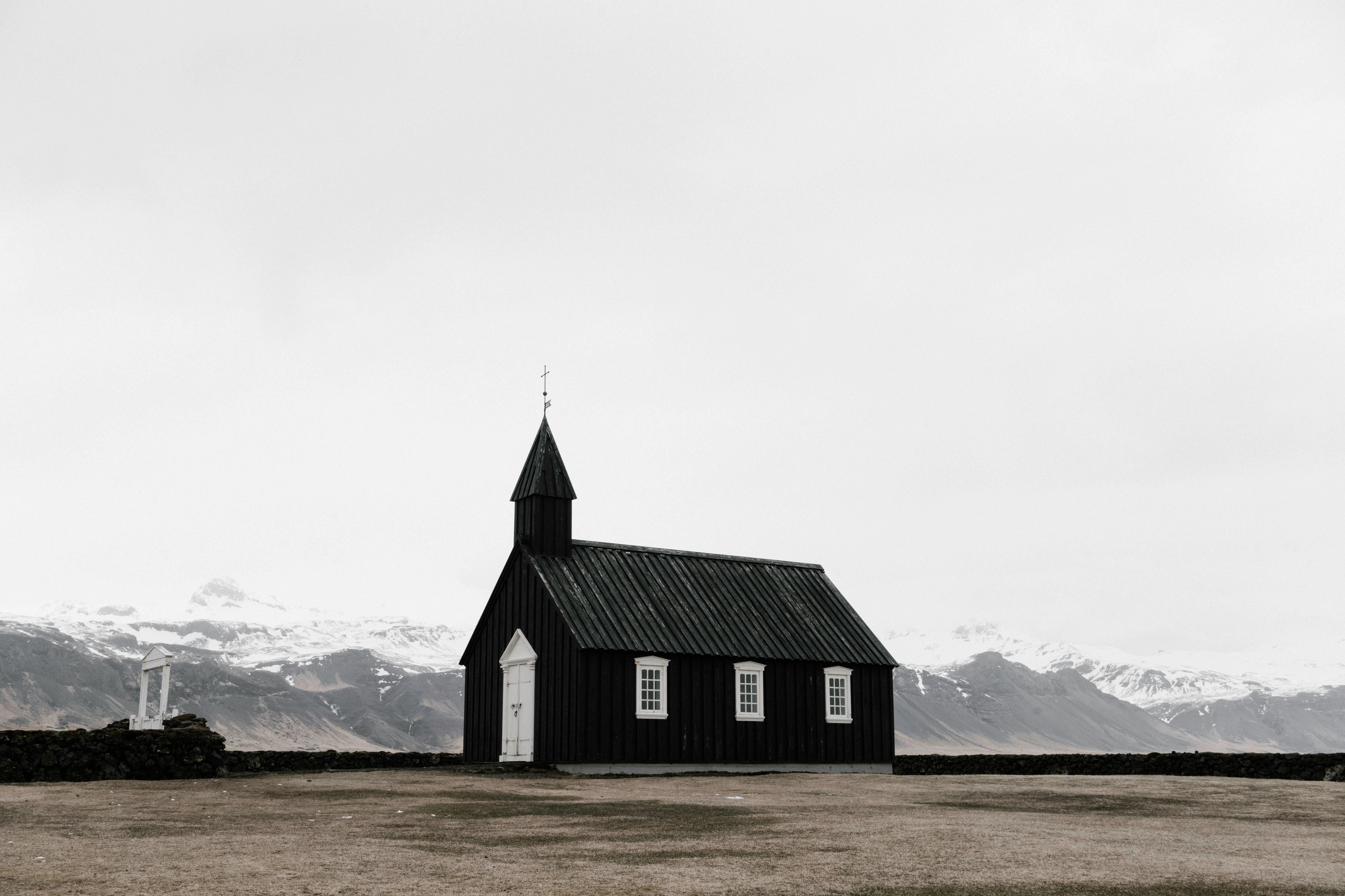 A small chapel in a plain with snowy mountains on the horizon